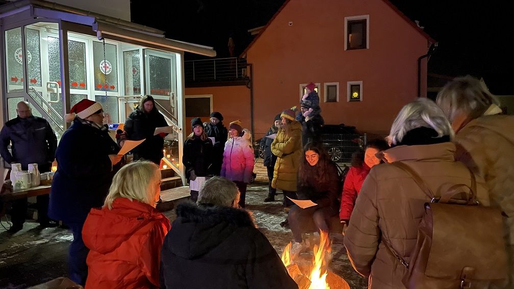 Bild: Menschen singen Weihnachtslieder am Lagerfeuer