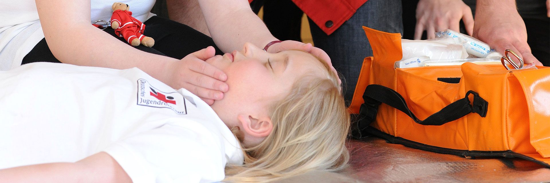 Bild: Bei einer Erste-Hilfe-Übung liegt ein Kind bewusstlos am Boden.